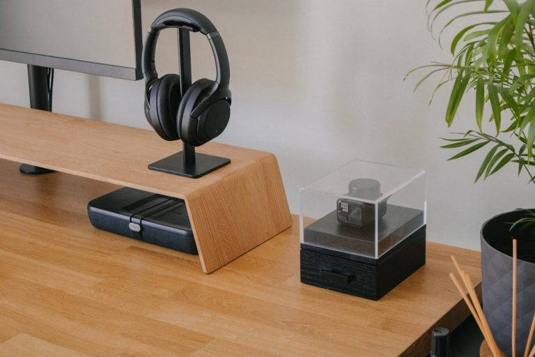 A modern desk setup featuring a monitor, headphones, and decorative items.